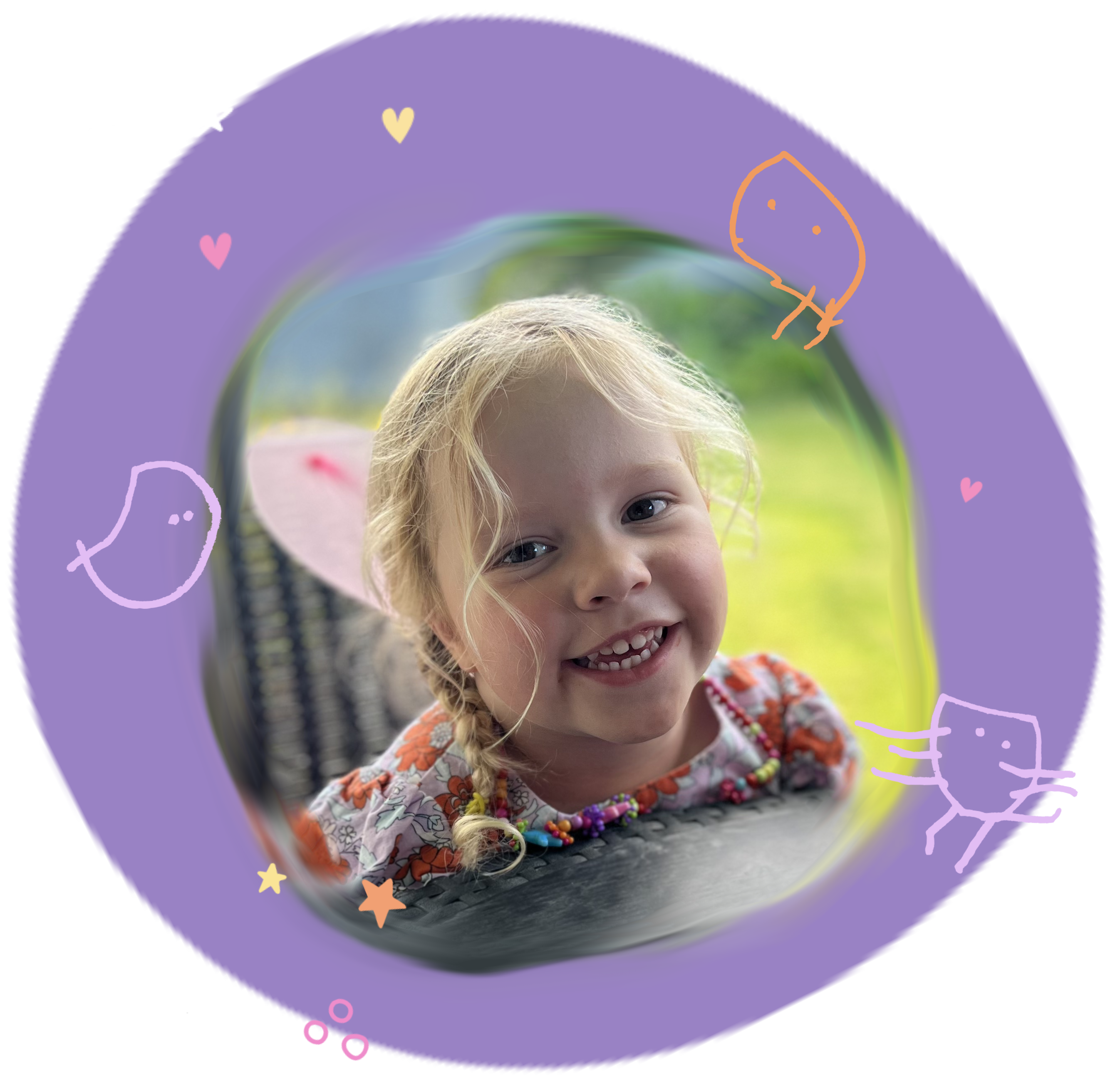 3 year old Effie Hurley from Dear Effie, the grief support charity, looking at the camera and smiling. She is surrounded by a purple circle background and her colourful doodle art of stick figure people that she had drawn herself as well as colourful love hearts and stars.